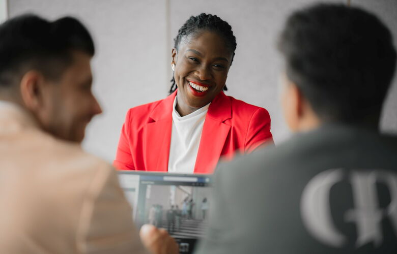 Personalberaterin im roten Blazer im Gespräch mit Kollegen – Grabowski & Rohmann Personalberatung Hamburg, professionelle Recruiting-Beratung