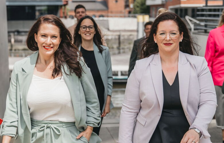 Geschäftsführerinnen und Team von Grabowski & Rohmann Personalberatung Hamburg im Business-Look – Frauen in mintfarbenem und hellgrauem Blazer laufen selbstbewusst Richtung Kamera, Symbol für moderne Personalberatung