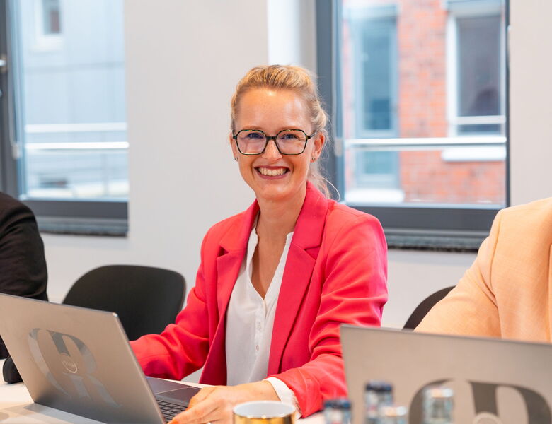 Personalberaterin von Grabowski & Rohmann Personalberatung Hamburg im pinkfarbenen Blazer arbeitet am Laptop – moderne Recruiting-Expertin mit Fokus auf Active Sourcing und Personalvermittlung