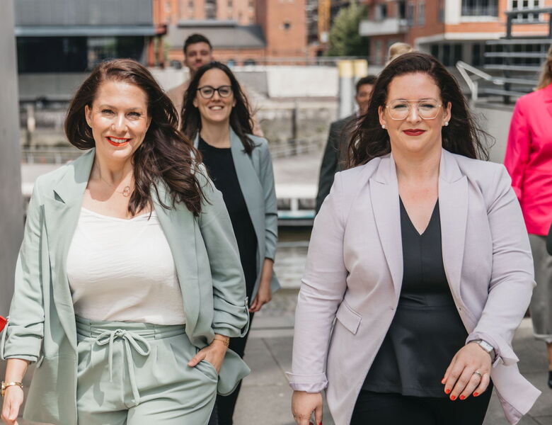 Geschäftsführerinnen und Team von Grabowski & Rohmann Personalberatung Hamburg im Business-Look – Frauen in mintfarbenem und hellgrauem Blazer laufen selbstbewusst Richtung Kamera, Symbol für moderne Personalberatung