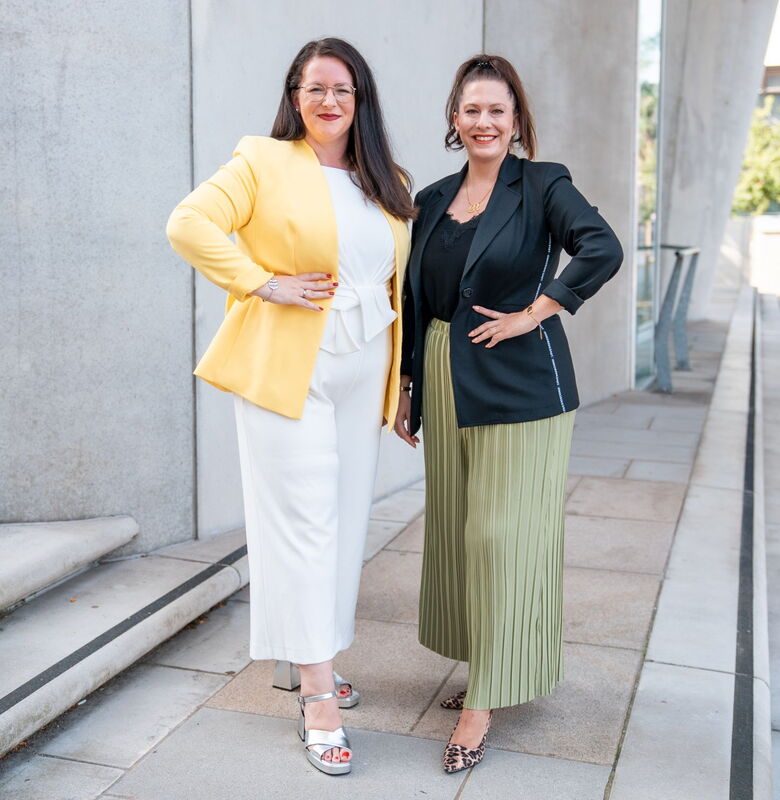 Geschäftsführerinnen von Grabowski & Rohmann Personalberatung Hamburg – eine trägt einen gelben Blazer, die andere einen schwarzen Blazer mit grünem Plisseerock – Expertinnen für Personalberatung und Executive Search